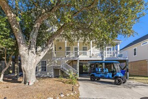 A two-story building with a covered garage and a tree in front.