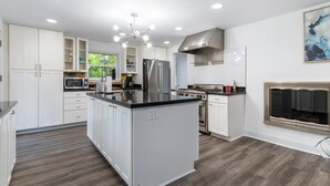 A modern kitchen with white cabinetry, stainless steel appliances, and a central island.