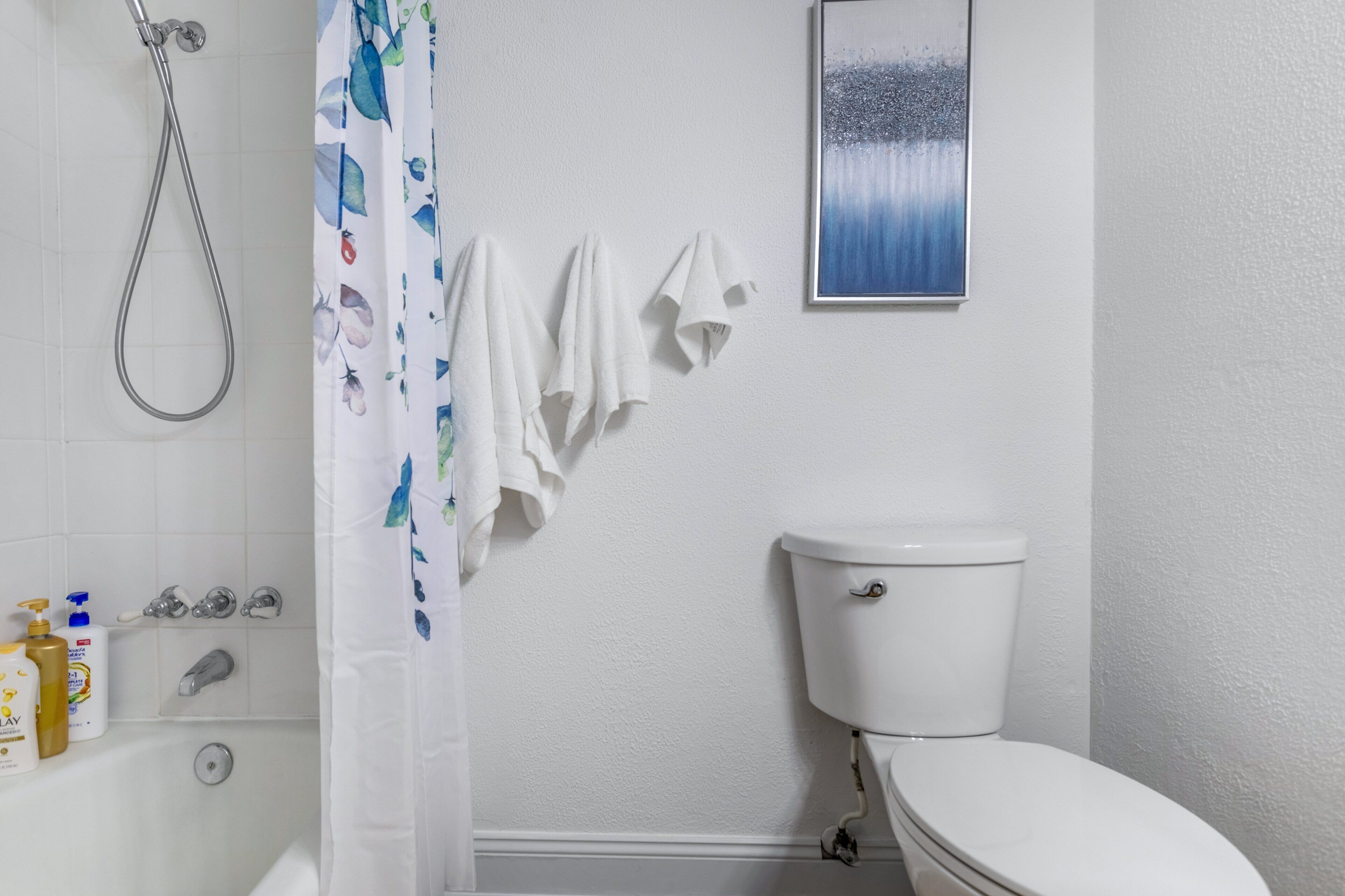A bathroom with a toilet, shower, and a wall-mounted sink.