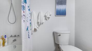 A bathroom with a toilet, shower, and a wall-mounted sink.