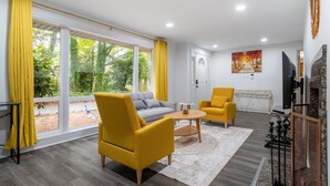 A modern living room with a sofa, two yellow armchairs, a coffee table, and a fireplace.