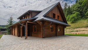 A wooden cabin with a sloped roof, large windows, and a stone-paved entrance. - Tranquil Villa in Velke Karlovice (Velké Karlovice)
