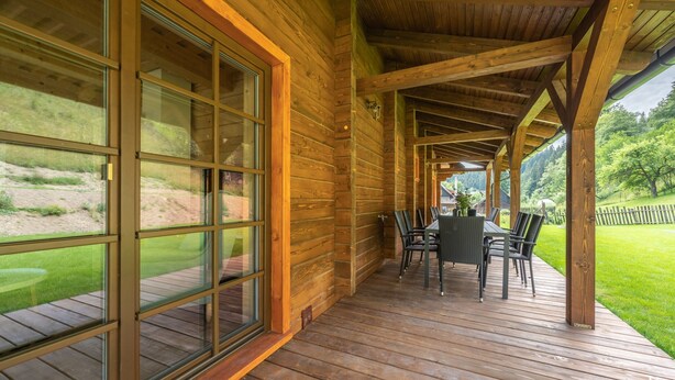 A wooden deck with a table and chairs, large windows, and a view of a grassy area. - Tranquil Villa in Velke Karlovice (Velké Karlovice)