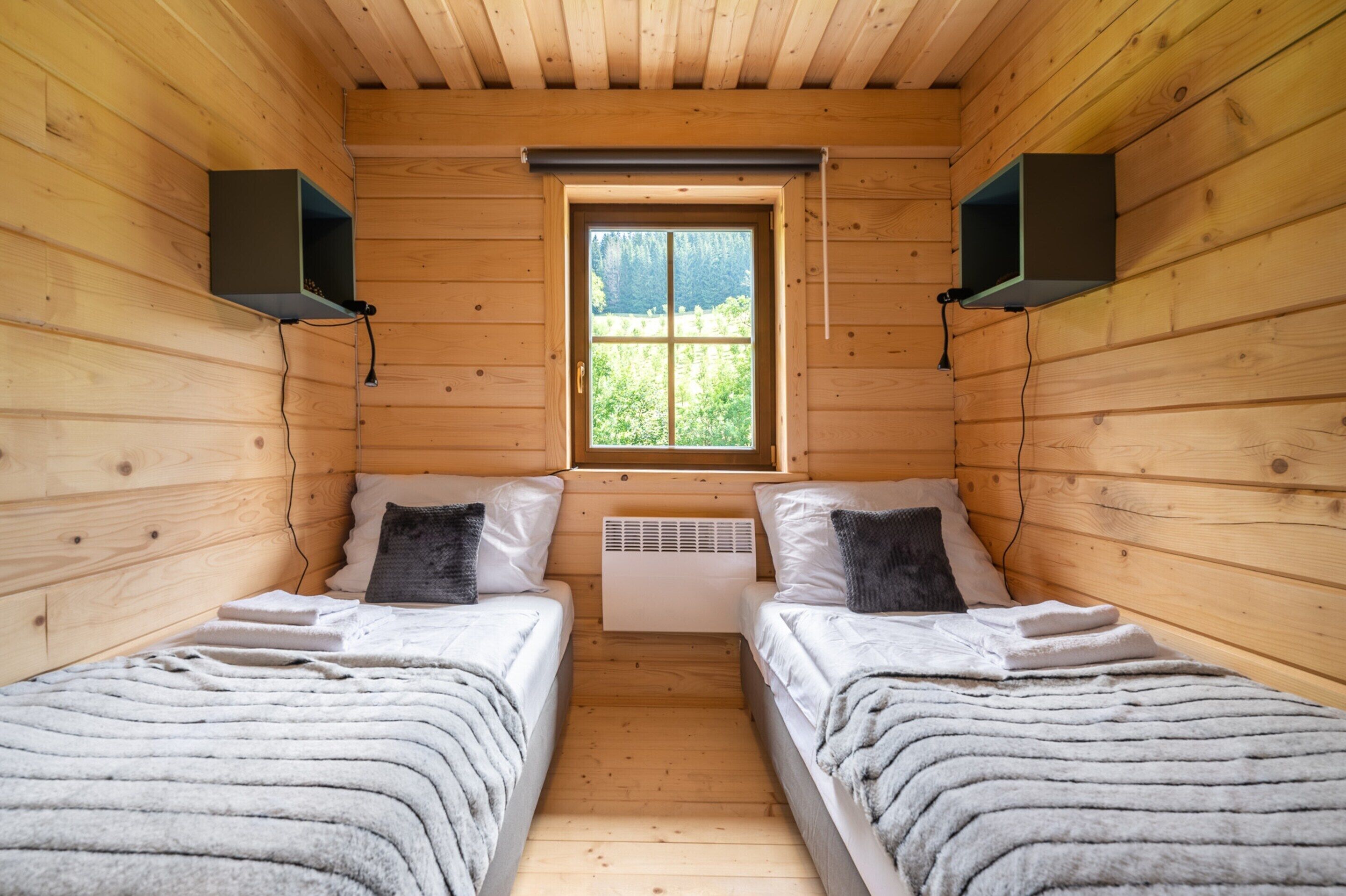 A cabin with two beds, a window, and a wall-mounted heater.