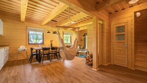 A wooden interior with a dining area, a hammock, and a door with a window. - Tranquil Villa in Velke Karlovice (Velké Karlovice)