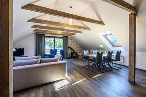 Ein Schlafzimmer im Dachgeschoss mit Schlafkoje, Essbereich und Wohnzimmer mit Sofa und Kamin.