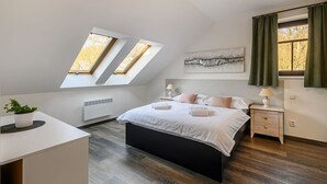 Un dormitorio con tragaluces, una cama, una mesita de noche, una lámpara y una planta en maceta.