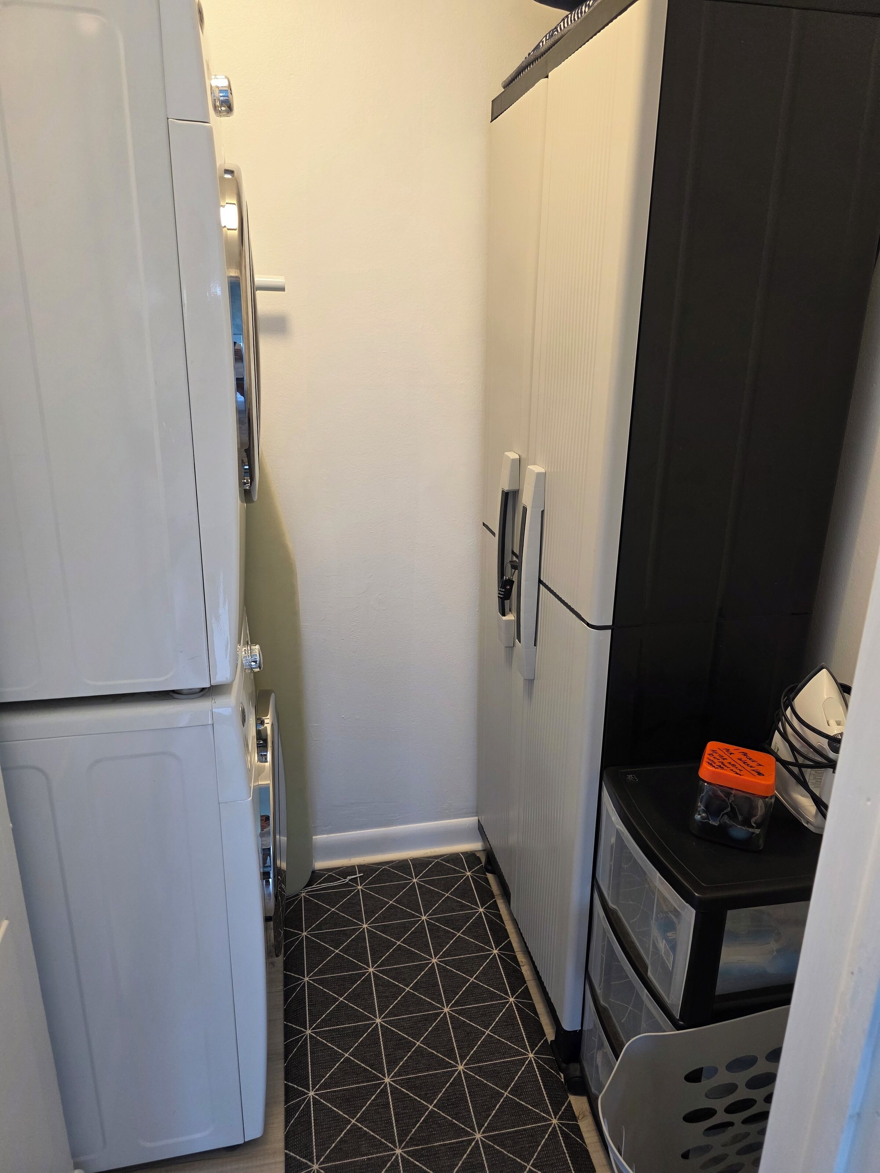 A compact kitchen with a refrigerator, a microwave, and a small countertop with a trash bin.