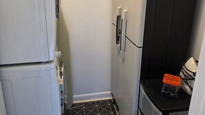 Una cocina compacta equipada con refrigerador, microondas y un pequeño mostrador con un cubo de basura.
