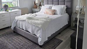 Un dormitorio con cama, mesitas de noche, lámpara, ventana y espejo.