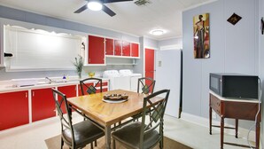 A compact kitchen with red cabinets, a wooden dining table, and a ceiling fan. - Walk to 1st Street: Family Home in Thibodaux! (Thibodaux)
