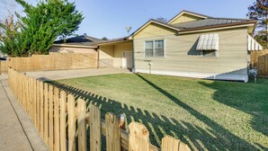 A single-story house with a fenced yard, a front door, and a satellite dish. - Walk to 1st Street: Family Home in Thibodaux! (Thibodaux)