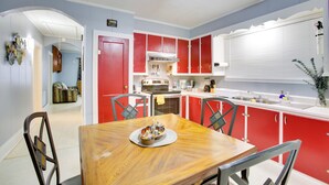 A kitchen with red cabinets, a wooden dining table, and a ceiling fan. - Walk to 1st Street: Family Home in Thibodaux! (Thibodaux)