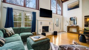 A spacious living room with a large sectional sofa, a fireplace, and a television mounted on the wall.