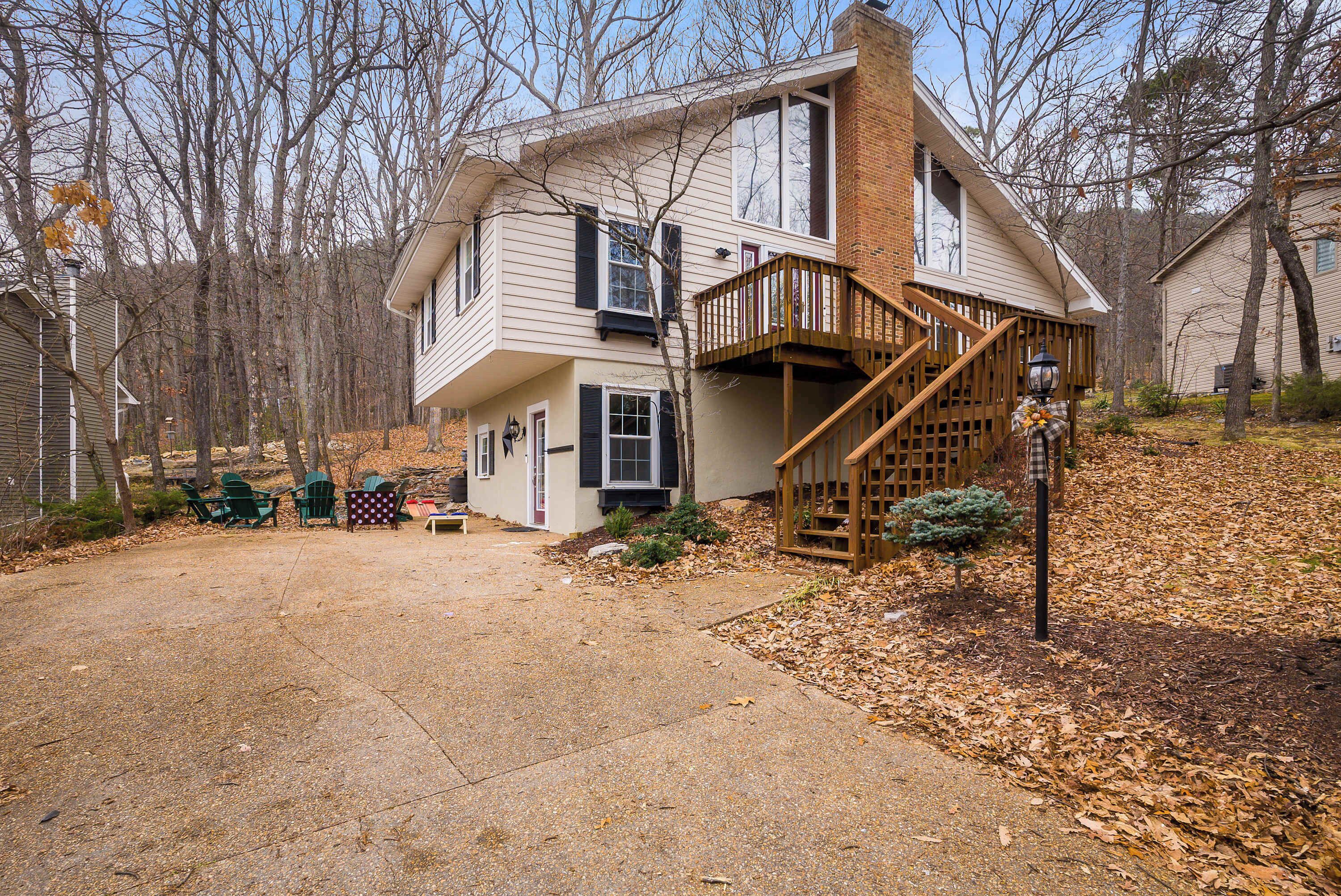 A two-story house with a front porch, a wooden staircase, and a small front yard with leaf-covered ground.