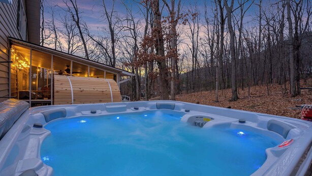 A hot tub with a wooden deck and a house in the background.