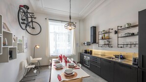 A modern kitchen with a dining area, featuring a bicycle mounted on the wall, a large window, and built-in shelves. - Stylish 3 Bd 3 Bath Duplex In Brussels (Brussels)