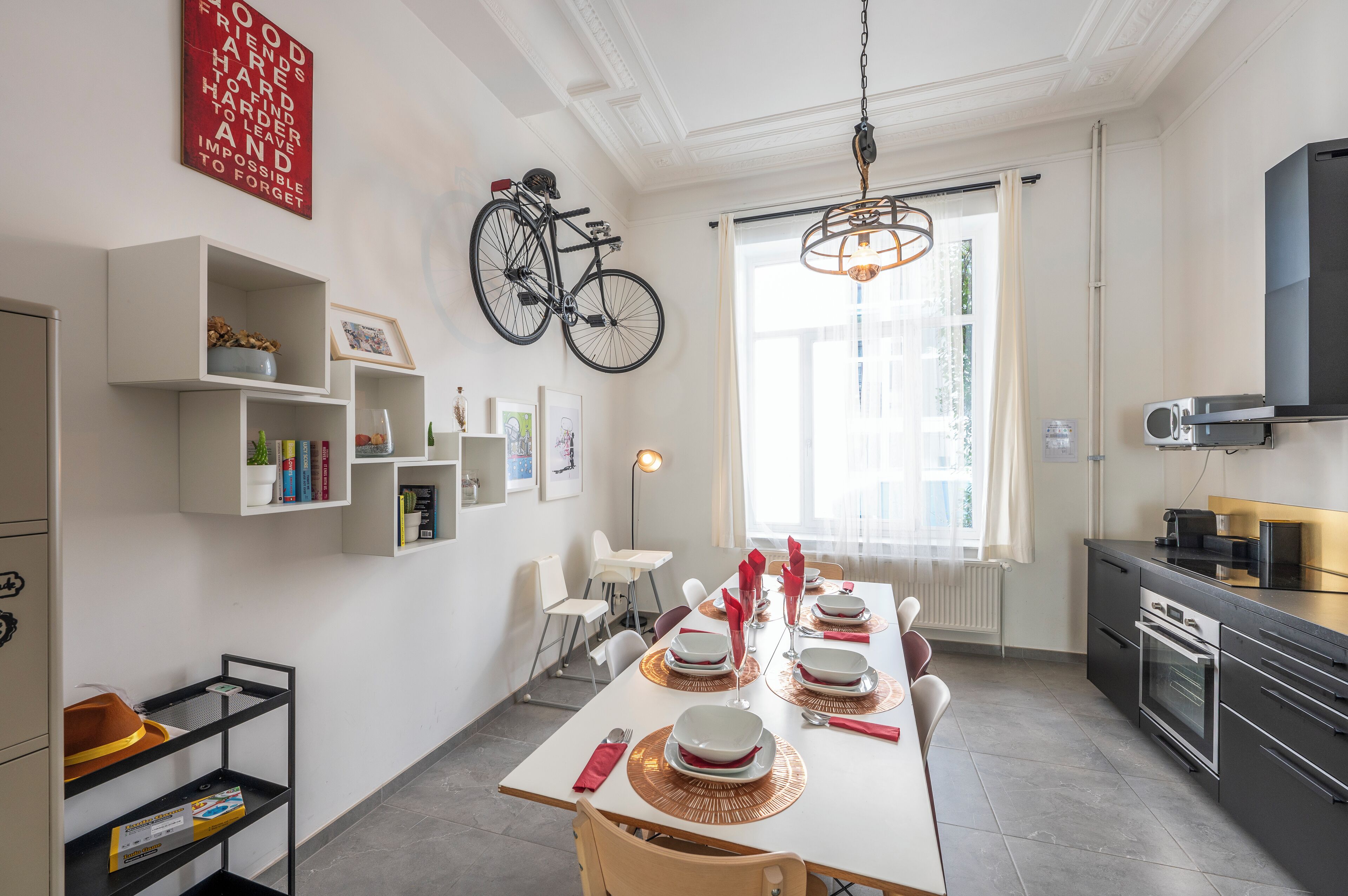 Een moderne keuken en eetruimte met een groot raam, een aan de muur bevestigde fiets en een eettafel gedekt voor vier personen.