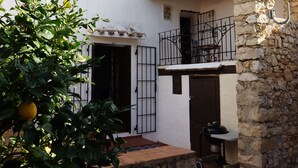 Ein Innenhof mit einer Steinmauer, einem kleinen Garten und einem Gebäude mit einem Ziegeldach und einem Balkon.