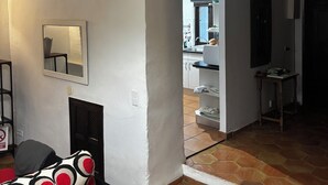 Ein Wohnzimmer mit Kamin, einer Couch mit roten und schwarzen Mustern sowie ein Essbereich, der durch einen offenen Durchgang sichtbar ist.