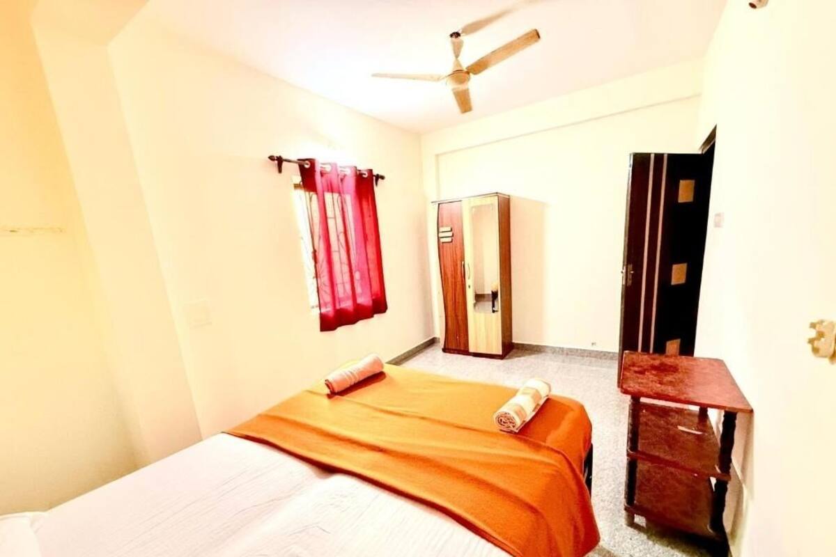 Une chambre à coucher avec un lit, un ventilateur de plafond, une armoire et un miroir.