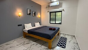 A bedroom with a bed, ceiling fan, air conditioning unit, window, and marble flooring. - The Village Harmony by Red Rose (Canacona)