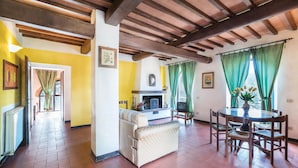 A cozy living room with a fireplace, a sofa, a dining table with chairs, and a television.