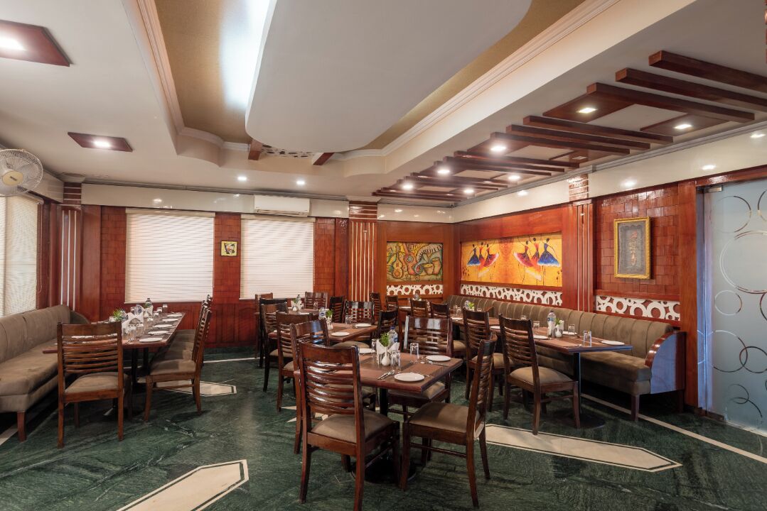 A dining area with multiple tables and chairs, wooden paneling, and artwork on the walls.