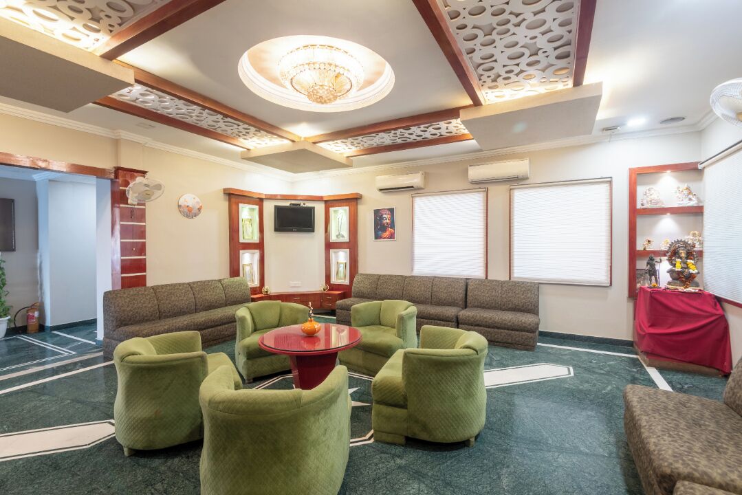 A lobby with a green sofa set, a red coffee table, and a chandelier.