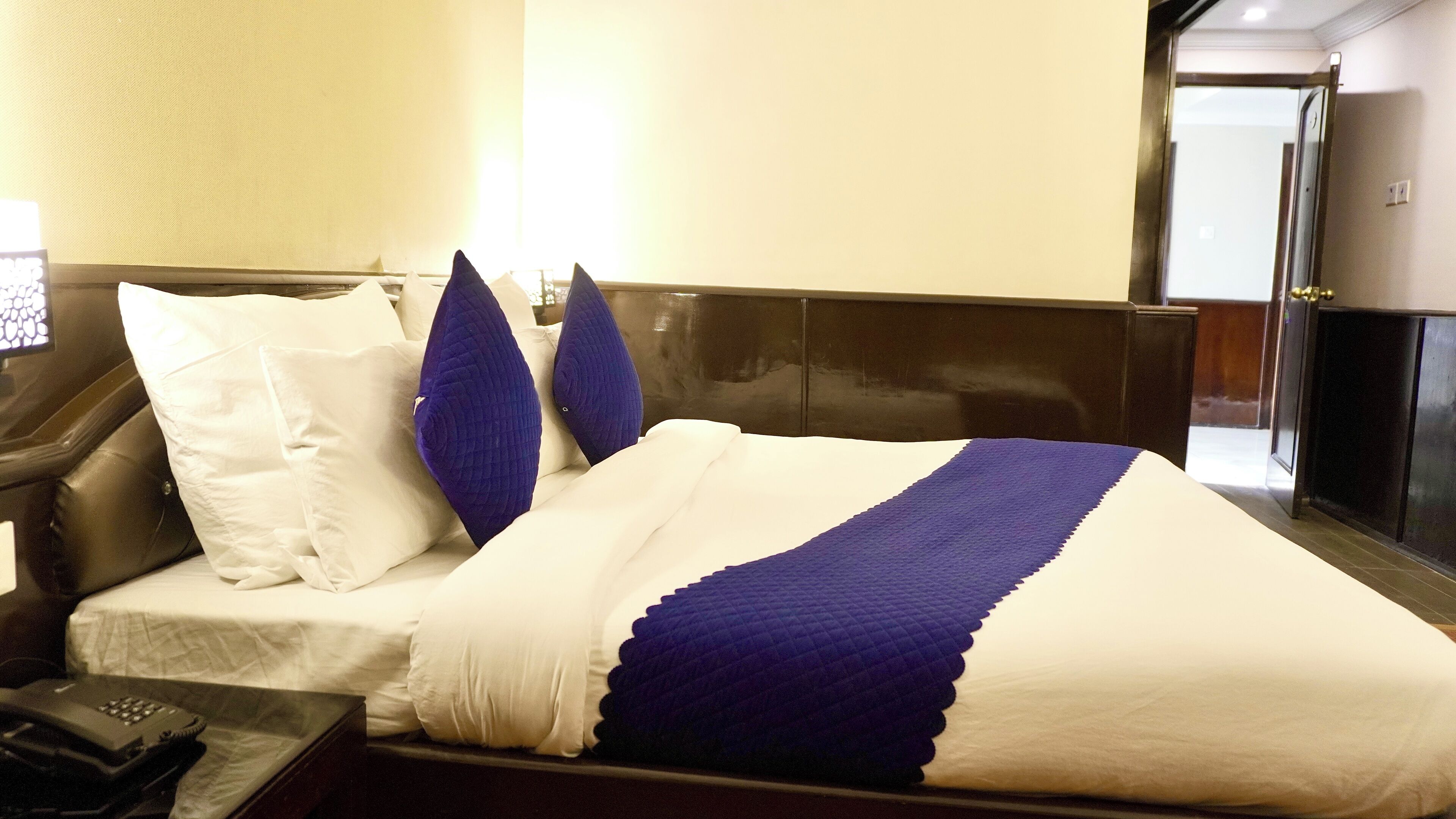 Una habitación de hotel con una cama, una mesita de noche y un teléfono.