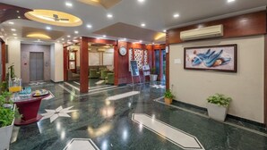 A hotel lobby with a marble floor, a reception desk, a clock, and a framed artwork on the wall. - DLS Park Grace (Haridwar)