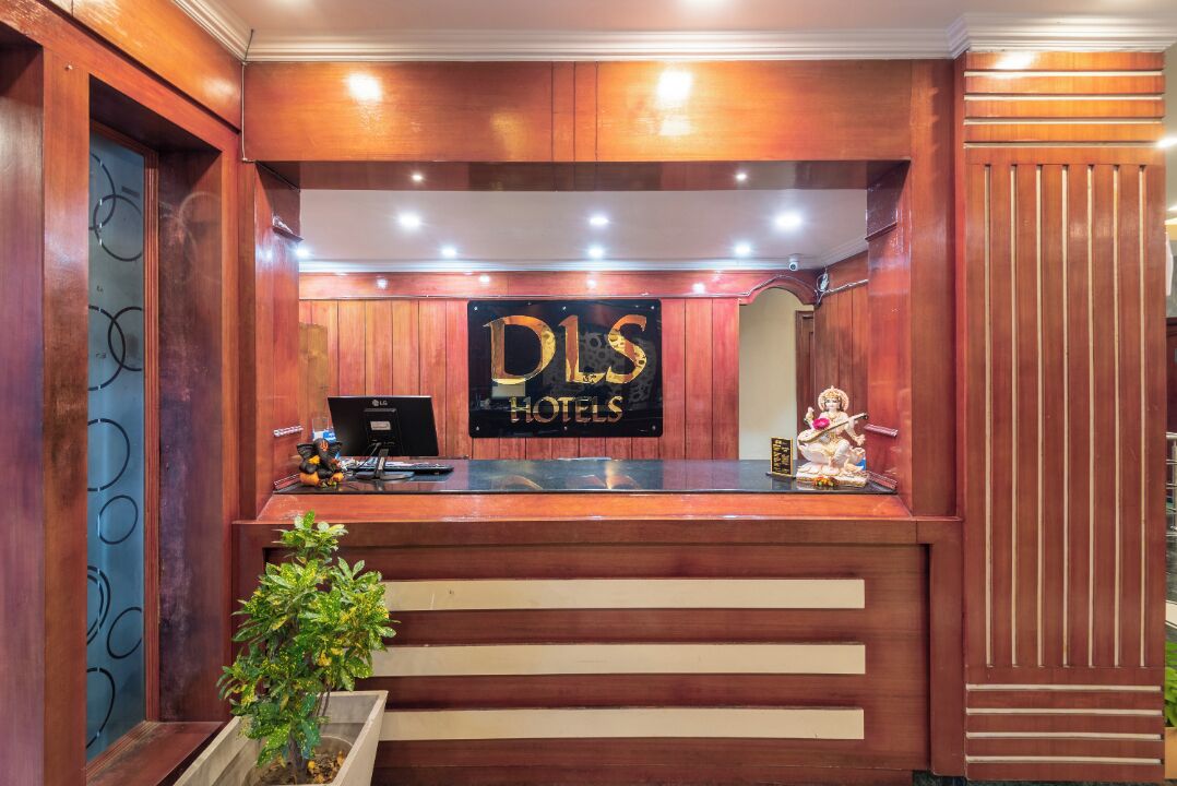 Un comptoir d’accueil avec une enseigne indiquant « DLS HOTELS » et une petite statue posée sur le comptoir.