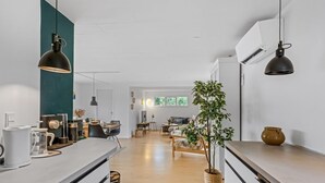 Une cuisine moderne dotée d’un îlot central, de luminaires suspendus et donnant sur l’espace de vie.
