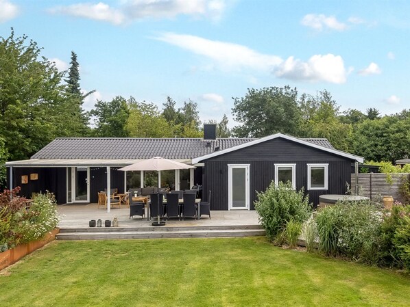 Une maison moderne dotée d’un patio, d’un espace salon couvert et d’une pelouse bien entretenue.