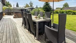 Une terrasse avec une table et des chaises, un parasol et un jacuzzi.
