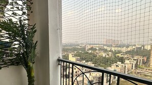 Un balcón con vista a un paisaje urbano, una planta en maceta y un muro decorativo.