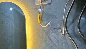 Un baño con encimera de mármol, cabina de ducha con vidrio y un set de artículos de aseo llamado "MORNING KIT" sobre la encimera.