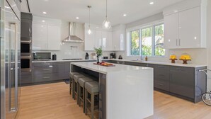 A modern kitchen with a large island, stainless steel appliances, and bar stools.