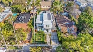 An aerial view of a residential area with modern houses, a swimming pool, and well-maintained gardens.