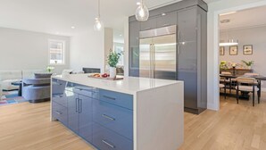 A modern kitchen with a central island, built-in appliances, and pendant lighting.