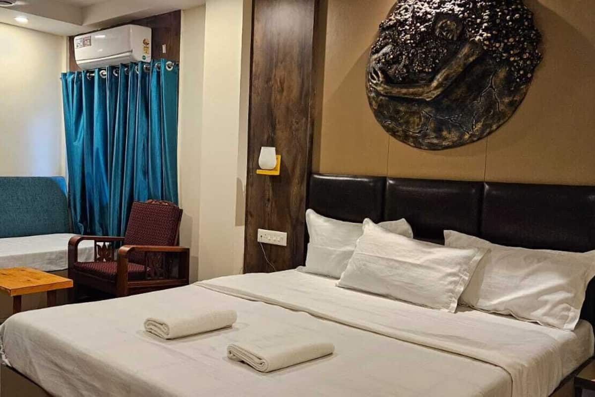 Une chambre d’hôtel comprenant un lit, un canapé-lit, une chaise et un climatiseur fixé au mur.