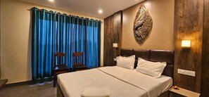Una habitación de hotel con una cama grande, dos mesitas de noche, una lámpara de pared y una cortina.