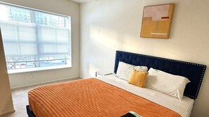 Een slaapkamer met een groot bed, een raam met zonwering en een schilderij aan de muur.