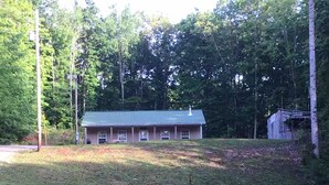 Une maison dotée d’un toit végétalisé, entourée d’une cour verdoyante et d’arbres.