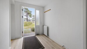 A hallway with a wooden floor, a door leading outside, and a radiator on the wall. - Stunning home in Nexø with WiFi (Nexø)