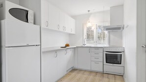 A modern kitchen with white cabinetry, a built-in oven, and a window providing natural light. - Stunning home in Nexø with WiFi (Nexø)