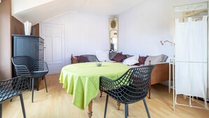 Een kamer met een bed, een eettafel met stoelen, een kledingkast en een spiegel aan de muur.
