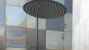 Een douche met een regendouche en een handdouche, bevestigd aan een betegelde muur.