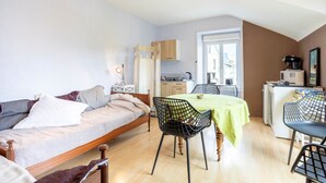 Een kleine kamer met een bed, een eettafel en een kitchenette.