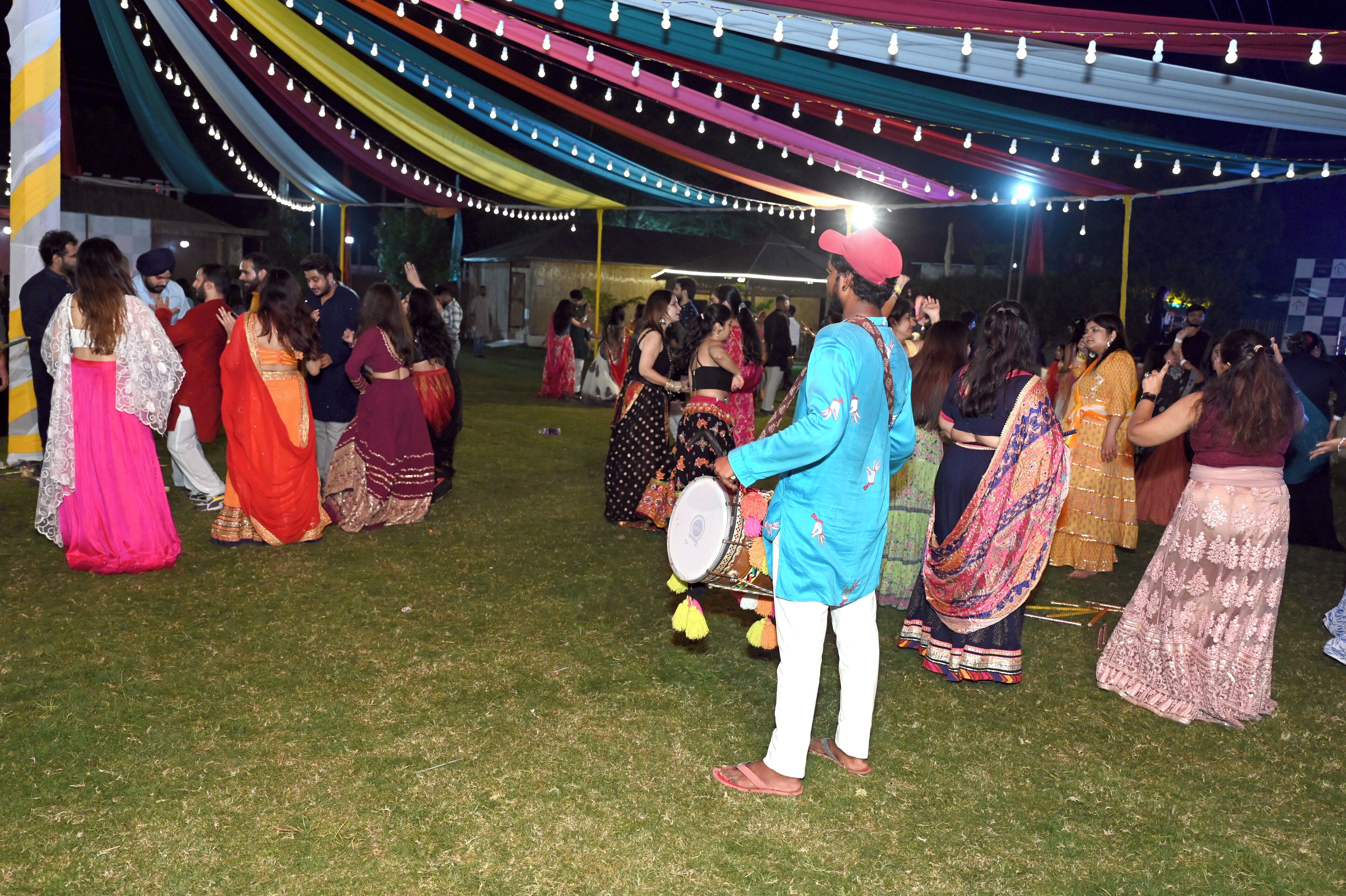 A group of people dancing under a tent with colorful drapes and string lights.